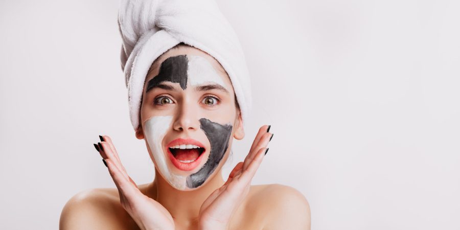 Joyful girl with face mask looks at camera in surprise. Green-eyed woman posing on white background after washing her hair